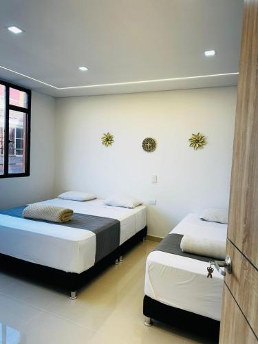 two beds in a room with white walls at Aero Hotel Boutique in Bogotá
