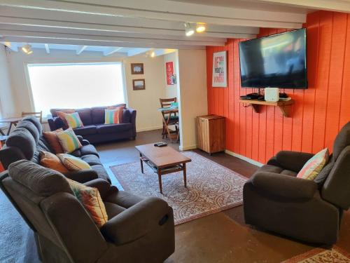 a living room with couches and a flat screen tv at Flat Hills Tourist Park in Ruahine
