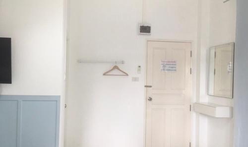 a white hallway with a white door and a mirror at Thirty Tree Garden House in Chumphon