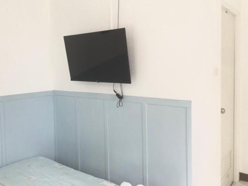 a flat screen tv on a wall above a bed at Thirty Tree Garden House in Chumphon