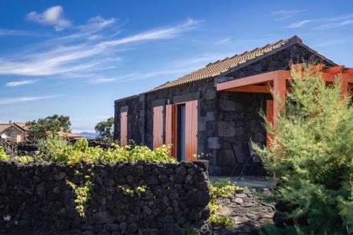 a small black stone house with a stone wall at Paraíso do Triângulo in Lajido