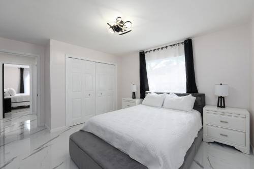ein weißes Schlafzimmer mit einem großen Bett und einem Fenster in der Unterkunft Luxury Style townhome with Pool - 1 Miles to Bucs Stadium in Tampa
