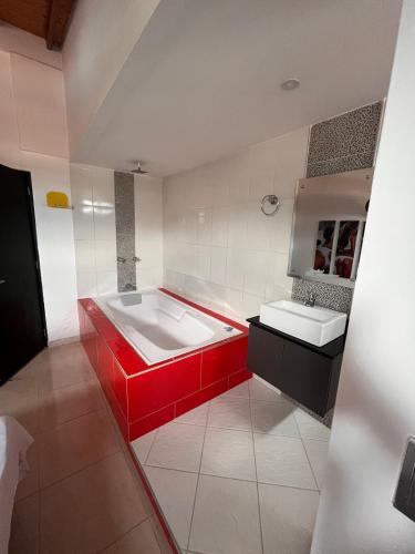 a bathroom with a red tub and two sinks at Hotel Los Ángeles in Bello