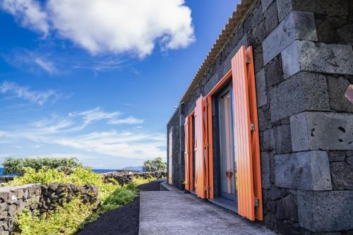 a stone house with orange doors and a stone wall at Paraíso do Triângulo in Lajido