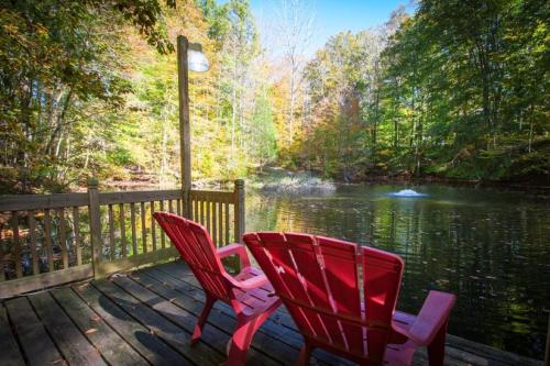 two red chairs sitting on a deck next to a lake at A Relaxation Station in Nashville