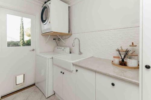 a white kitchen with a sink and a window at Cosy Country Cottage in Alstonville