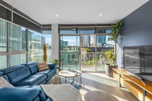 a living room with a blue couch and large windows at Stadium Escape - A Contemporary Beachside Retreat in Wollongong