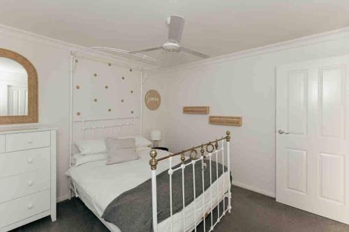 a bedroom with a white bed and a white dresser at Cosy Country Cottage in Alstonville
