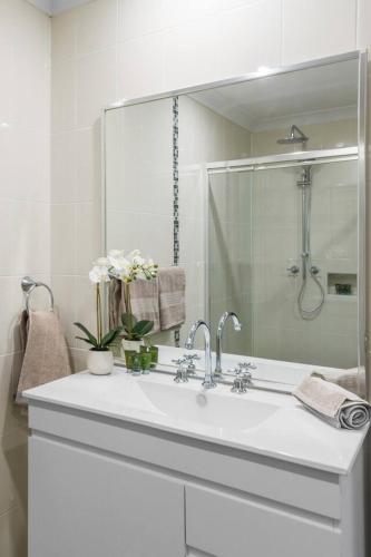 a white bathroom with a sink and a mirror at Stadium Escape - A Contemporary Beachside Retreat in Wollongong