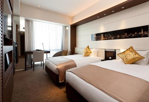 a hotel room with two beds and a desk at Solaria Nishitetsu Hotel Ginza in Tokyo