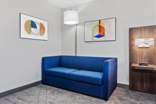 a blue couch in a room with paintings on the wall at Holiday Inn Express Hotel & Suites Chicago-Algonquin by IHG in Algonquin