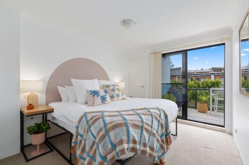 a bedroom with a bed and a large window at Chic Brookvale Unit-Big Balcony! in Sydney