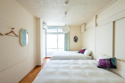 two beds in a room with a window at Pineapple Hotel in Naha
