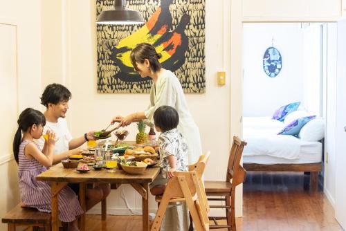 a woman and two children sitting at a table eating food at Pineapple Hotel in Naha
