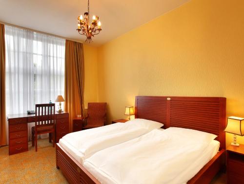 um quarto com uma grande cama branca e uma secretária em Hotel Bellmoor im Dammtorpalais em Hamburgo