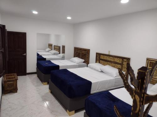 a row of four beds in a room at Casa La Riviera in Santa Rosa de Cabal