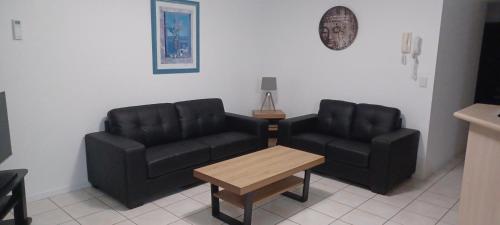 2 sillas negras y una mesa en la sala de estar en Blue Waters Apartments, en Gold Coast