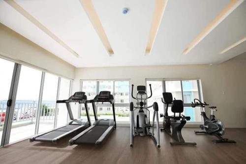 a gym with treadmills and ellipticals in a room with windows at A Marina Spatial 2BR , 2Showers, 1Balcony, 1 Storage Room in Dumaguete