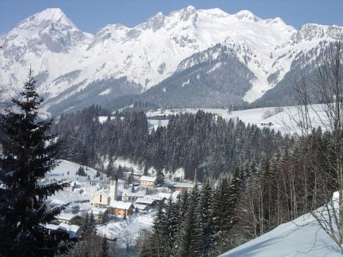 a snow covered mountain range with a town in the foreground at Pension Haus Rohrmoser in Annaberg im Lammertal