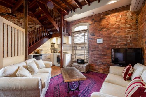 a living room with two couches and a brick wall at Bon Accord Boutique Accommodation in Sale