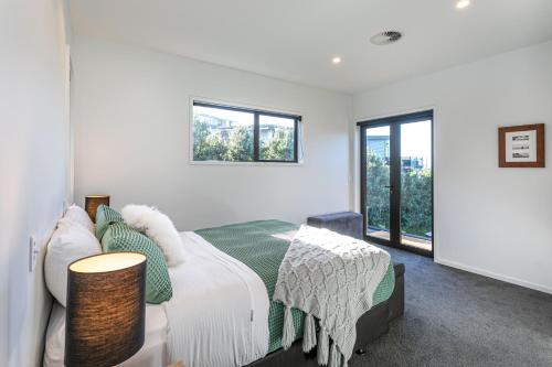 a white bedroom with a bed and a window at Hahei Heights in Hahei