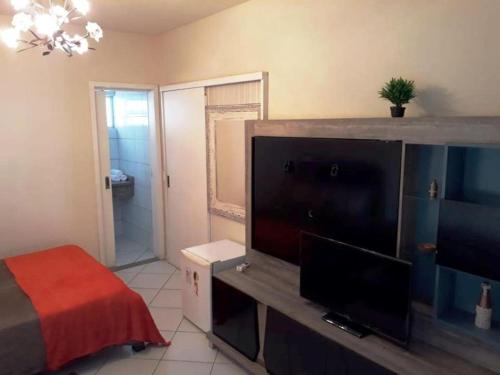a bedroom with a flat screen tv and a bed at Mansão Ouro Verde Beira Mar in Piçarras