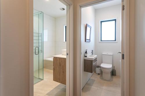 a bathroom with a glass shower and a toilet at Hahei Heights in Hahei