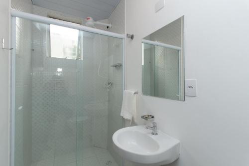 a white bathroom with a sink and a shower at Hotel Villa Jequitibá in Sao Paulo