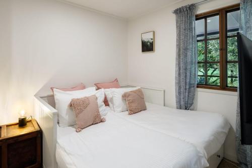 a bedroom with a white bed with pillows and a window at Grove Hinterland Retreat - 15 mins to beach in Kiels Mountain