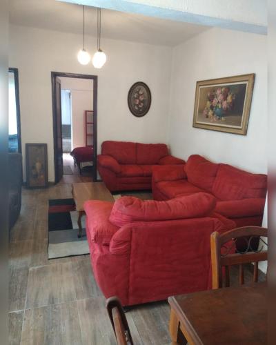 ein Wohnzimmer mit einem roten Sofa und einem Tisch in der Unterkunft Amplio y cómodo departamento in Mexiko-Stadt