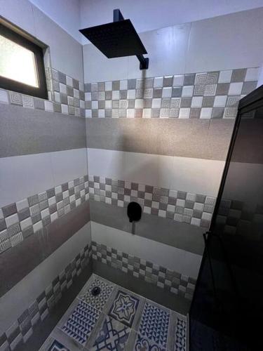 a tiled bathroom with a shower with a window at Casita Oropéndola in Monterrey