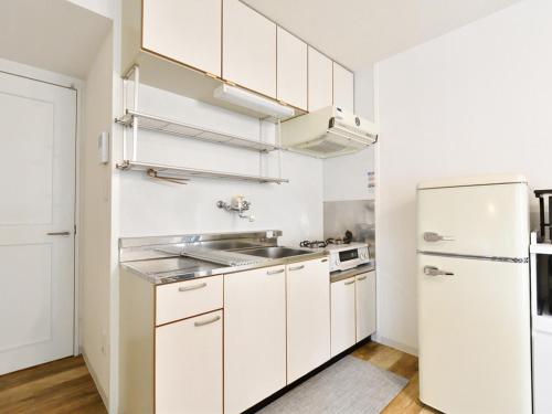a white kitchen with a sink and a refrigerator at シャトーひらぎし in Sapporo