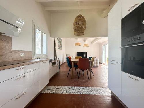 une cuisine avec des armoires blanches et une table avec des chaises dans l'établissement Villa rénovée 4 pièces 80m² avec patio privé et accès plage - La Palmyre - FR-1-705-71, aux Mathes