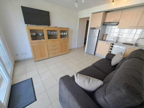 un salon avec un canapé et une cuisine dans l'établissement Appartement T2 avec Terrasse, Piscine et Parking Privé - Marseillan - FR-1-326-826, à Marseillan