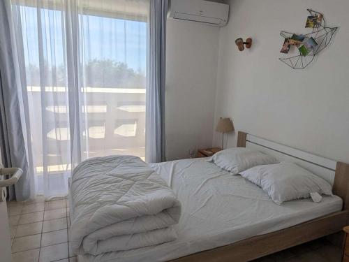 un lit défait dans une chambre avec une grande fenêtre dans l'établissement Duplex en bord de mer avec jardin privé et accès direct à la plage, climatisation, parking et internet. - FR-1-250-282, à La Grande Motte