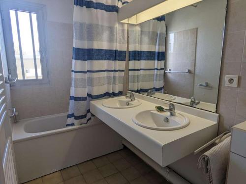 une salle de bain avec deux lavabos, une baignoire et un miroir dans l'établissement Duplex en bord de mer avec jardin privé et accès direct à la plage, climatisation, parking et internet. - FR-1-250-282, à La Grande Motte