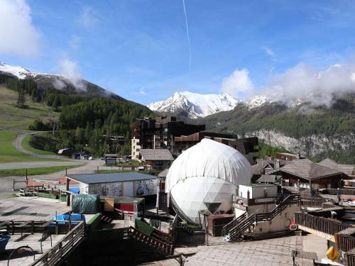 un grand bâtiment blanc en forme de dôme avec des montagnes en arrière-plan dans l'établissement Studio cosy pour 2 en centre station, vue sur les pistes - FR-1-322-629, aux Orres