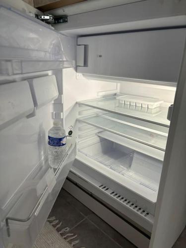 - un réfrigérateur ouvert avec une bouteille d'eau dans l'établissement Appartement tout équipé Centre Mulhouse, à Mulhouse