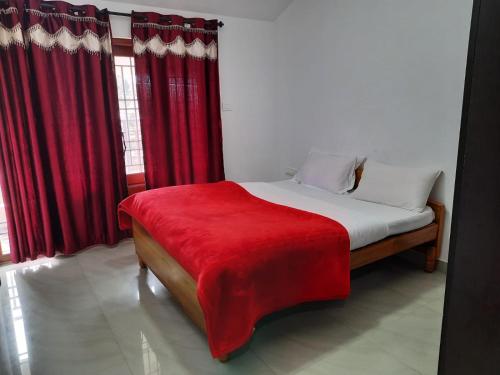 a bedroom with a bed with a red blanket on it at Neo Nirmal Residency in Ooty