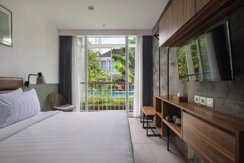 ein Schlafzimmer mit einem Bett und einem großen Fenster in der Unterkunft Rimbun Canggu Hotel in Canggu