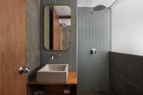 ein Badezimmer mit Waschbecken und Spiegel in der Unterkunft Rimbun Canggu Hotel in Canggu
