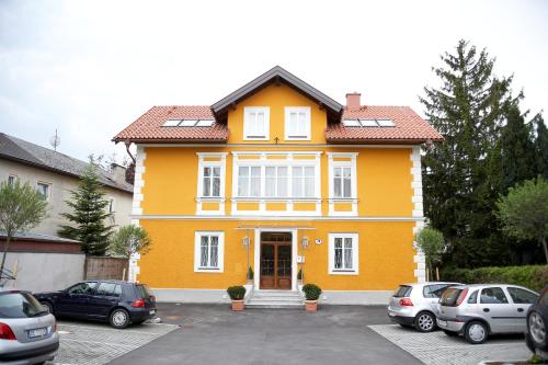 una casa amarilla con coches aparcados en un estacionamiento en Villa Ceconi by Das Grüne Hotel zur Post - 100% BIO en Salzburgo