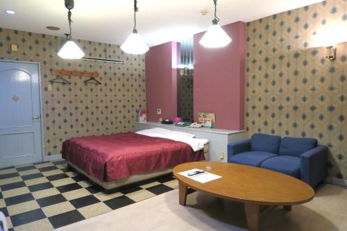 1 dormitorio con cama, mesa y sofá azul en Hotel Silk no Mori (Adult Only), en Tosu