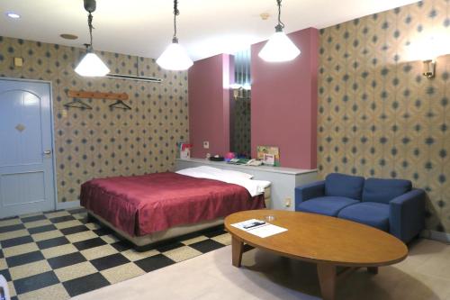 a bedroom with a bed and a table and a blue couch at Hotel Silk no Mori (Adult Only) in Tosu