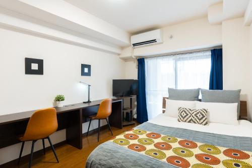 a bedroom with a bed and a desk with a computer at Grande es TENJIN in Fukuoka