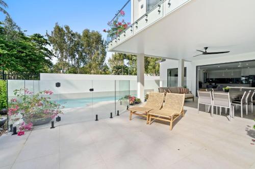 an outdoor patio with chairs and glass walls at Belle Escapes Beach Manor in Palm Cove