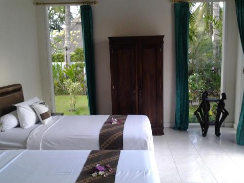 a bedroom with two beds and two large windows at Vista del Mar in Candidasa