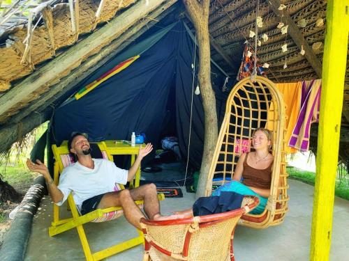Ein Mann und eine Frau sitzen in Hängematten in einem Zelt in der Unterkunft Delft Village Stay in Delft East
