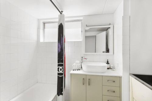 a white bathroom with a sink and a shower at Beachfront Retreat at Burleigh, Breezy and Cosy in Gold Coast