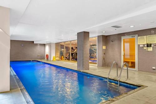 a large swimming pool with blue water in a building at 'The Hindmarsh' Hotel-style Pad with Hills Panorama in Adelaide